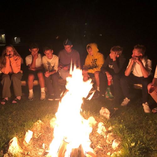 Schüler:innen vorm Lagerfeuer bei Nacht sitzend