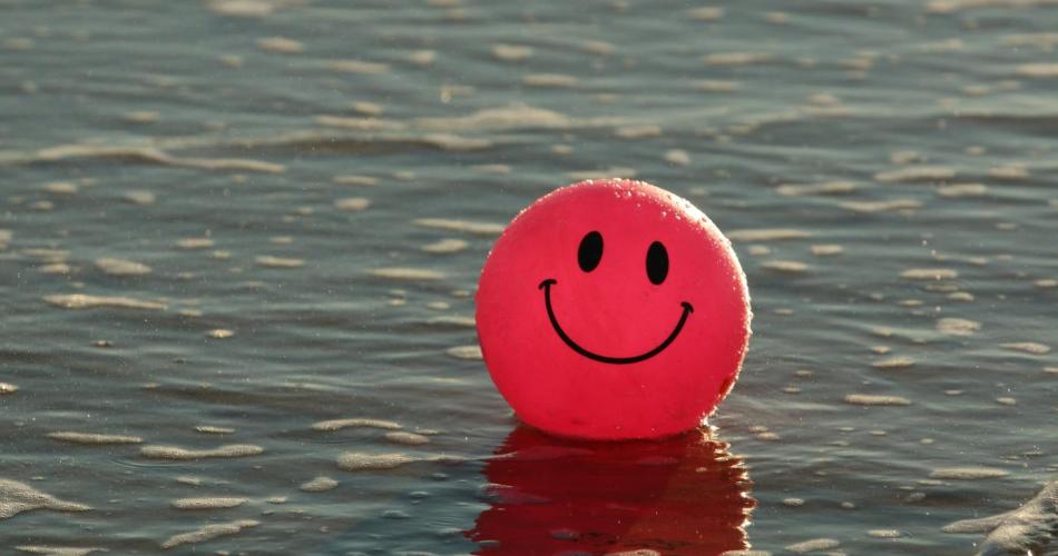 Roter Ball auf dem Wasser mit lachendem Gesicht aufgemalt
